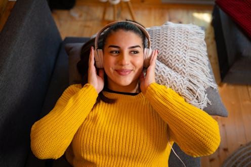 Smiling brunette listening to music and relaxing in a living room