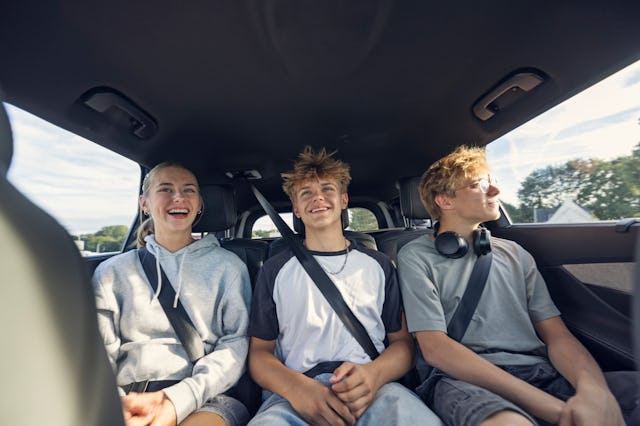 Three teenagers sit in the backseat of a car. Middle children, and those with siblings, scored highe...