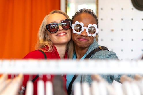 Women shopping in a thrift store in London's vibrant Shoreditch area have fun trying on some retro s...