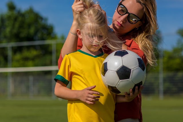 Soccer Mom preparing her blond daughter for football training