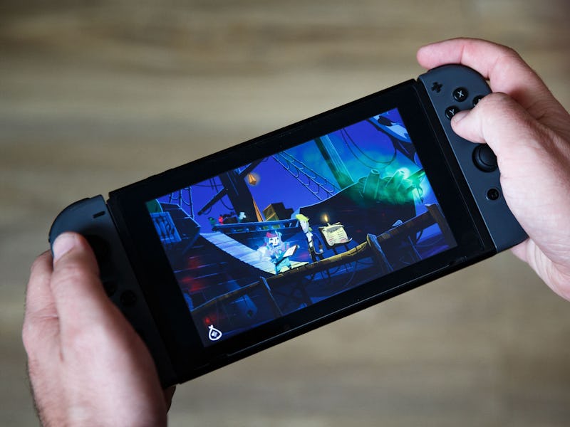 A photograph shows a screen of a Nintendo Switch console displaying the adventure video game «Return...