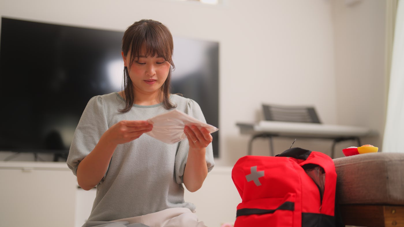 A woman is preparing an emergency bag in the living room at home.