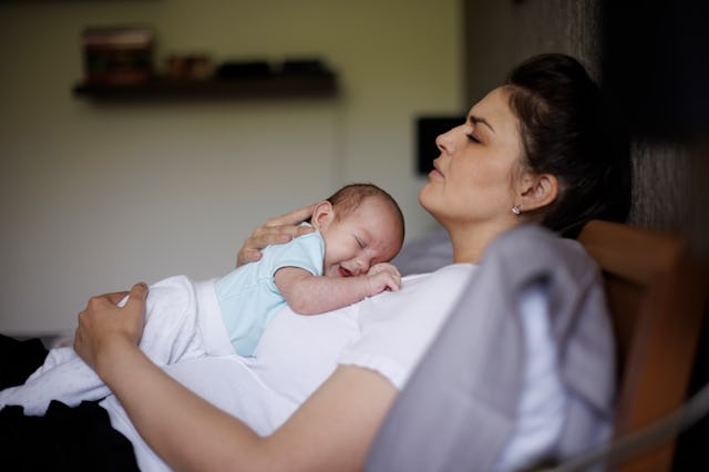 Exhausted mother holding her crying newborn baby. Postpartum depression