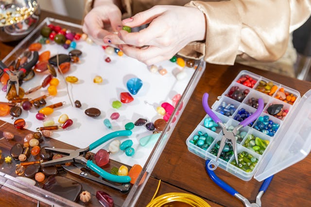 A Female Model Makes Jewelry using Beads, Pliers and Other Tools at a Workbench. In these photos sh...