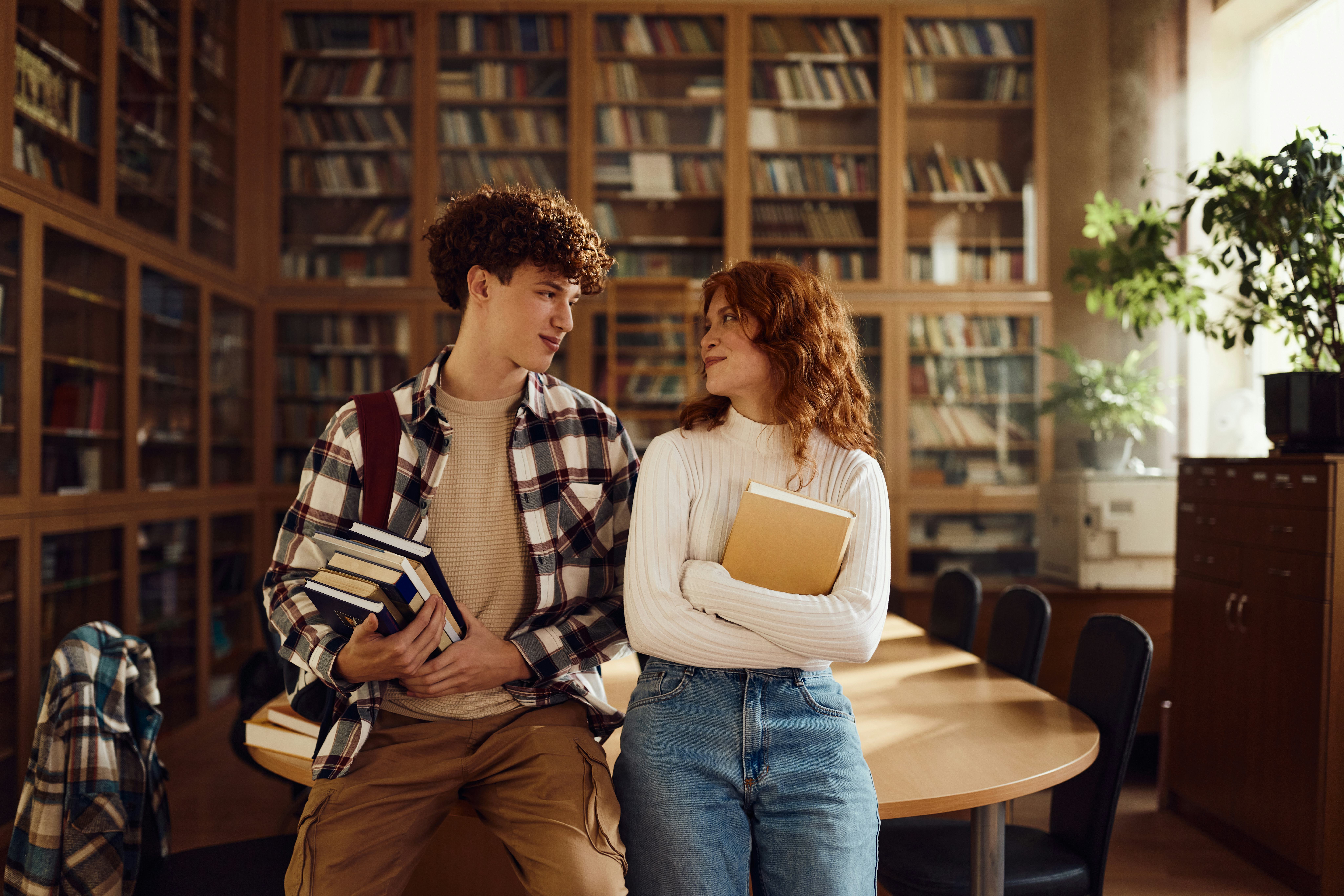 Smiling students communicating while being in library.