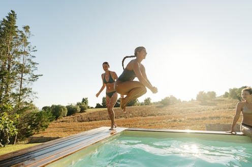 Photo of female friends jumping into the pool