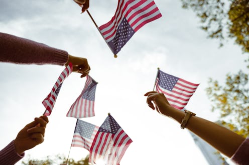 A group of people is waving small American flags at sunset. Concept for various topics like Happy Ve...