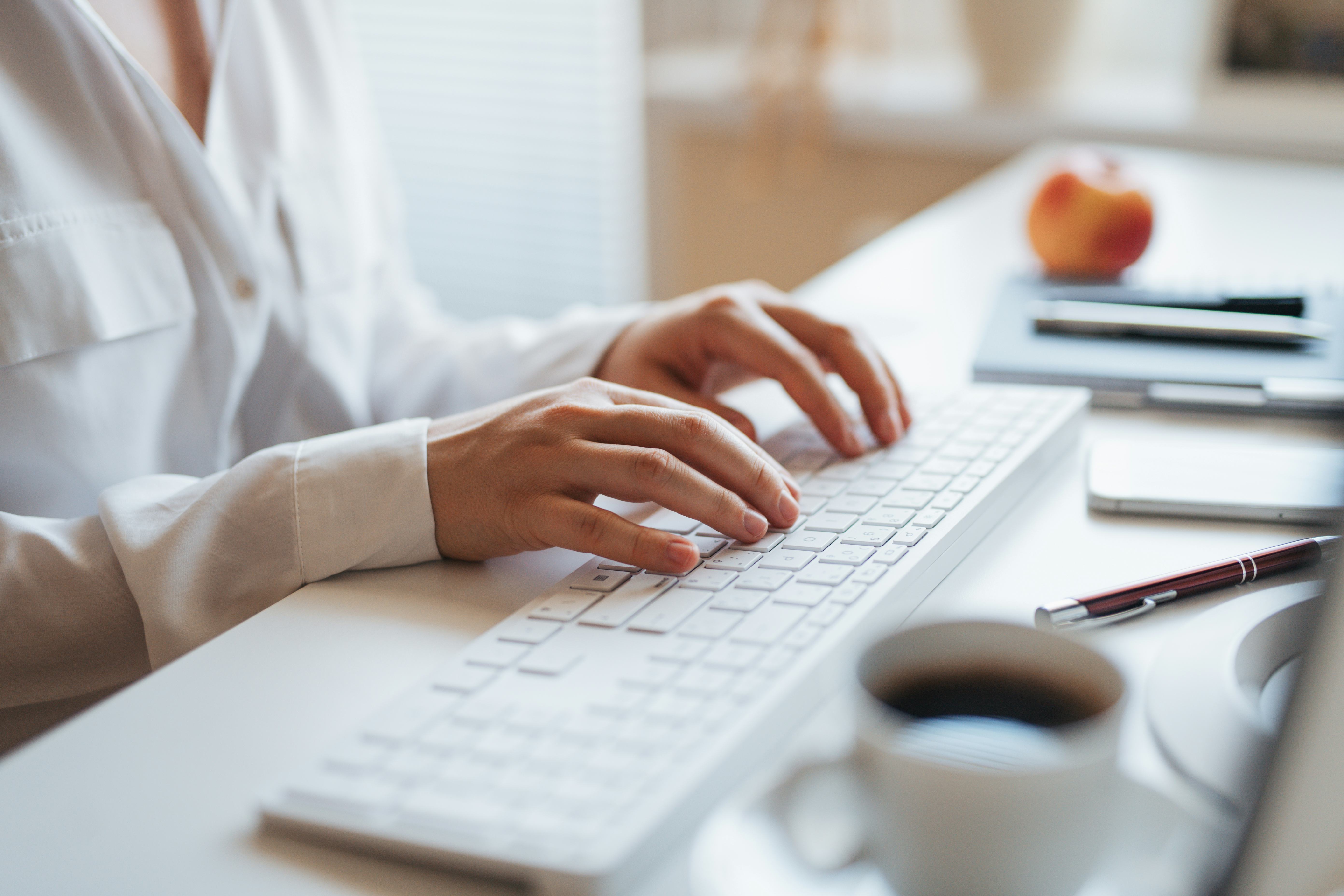 Hands on keyboard during remote work, close up on hands.
