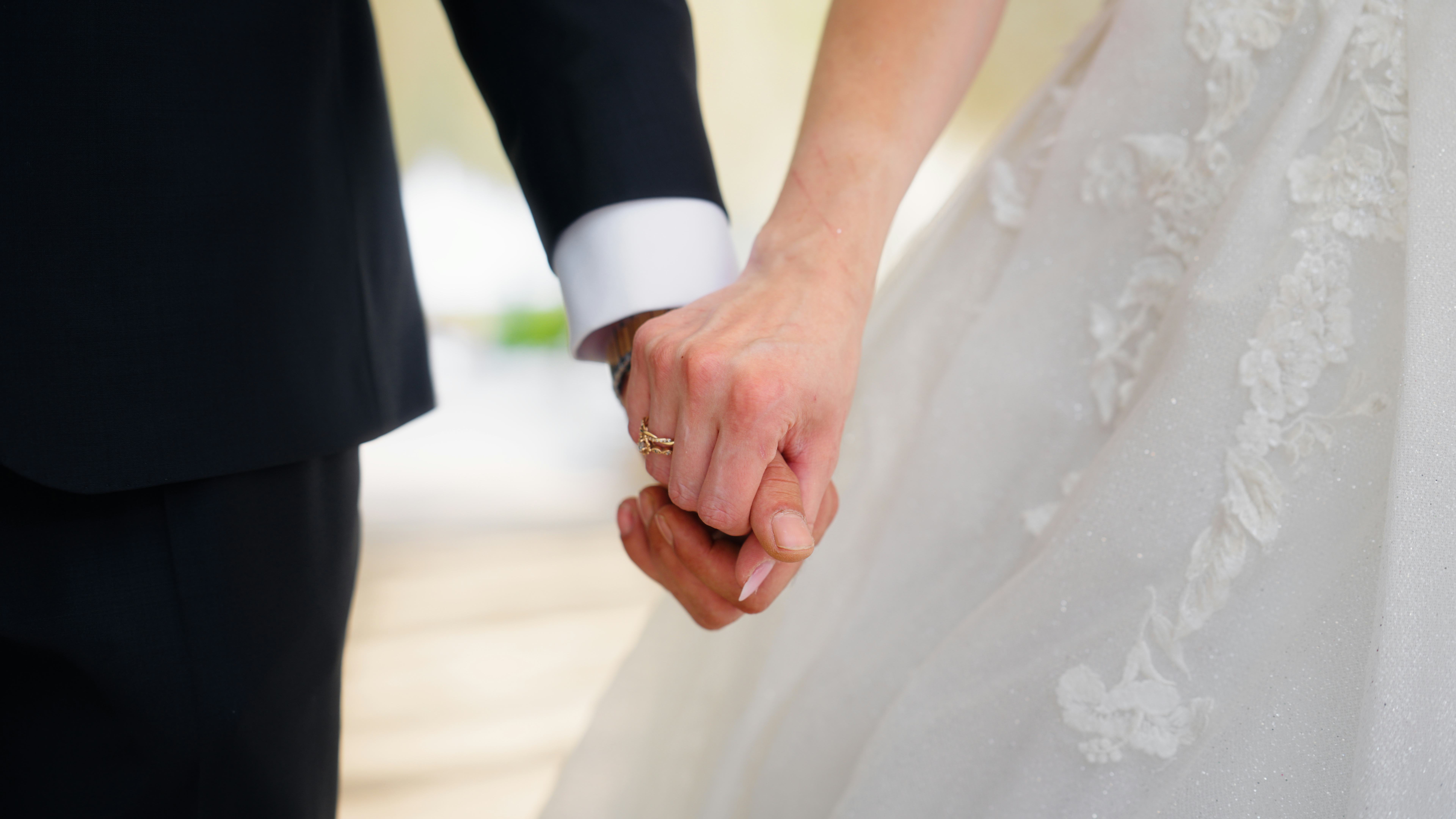 A close-up video of newlywed, young bride and groom, holding each other's hands. The wedding ring is...