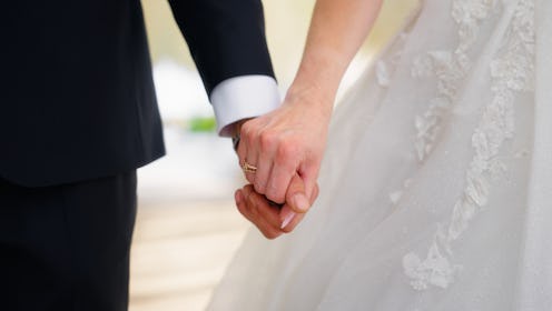 A close-up video of newlywed, young bride and groom, holding each other's hands. The wedding ring is...