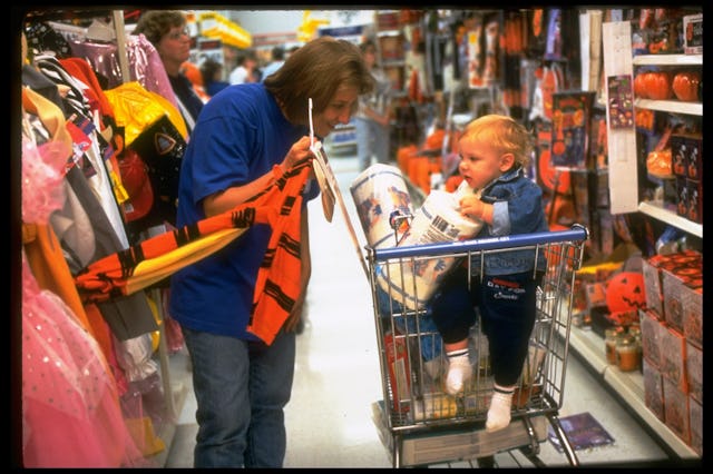Lori Lucas showing her shopping cart-riding son Sam Halloween costume at Wal-Mart, shopping stop in ...