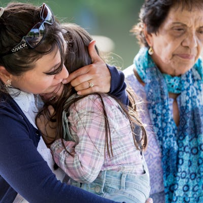 Caring mid adult mom comforts her upset little girl. The girl is crying while sitting in her mom's lap.