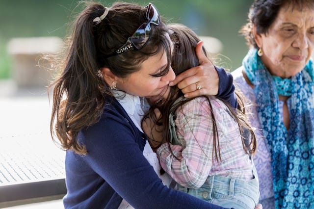 Caring mid adult mom comforts her upset little girl. The girl is crying while sitting in her mom's l...