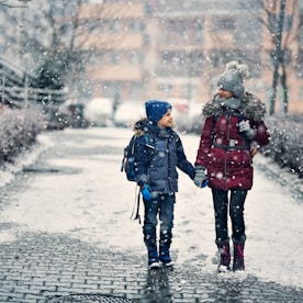 A bother and sister walk to school on winter day.