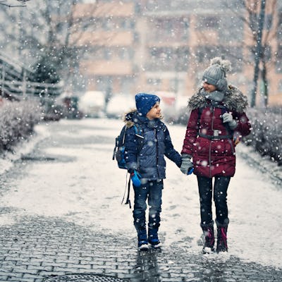 A bother and sister walk to school on winter day.