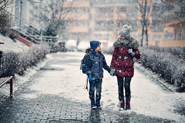 A bother and sister walk to school on winter day.