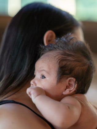 A new mom holds her newborn baby cheek to cheek.