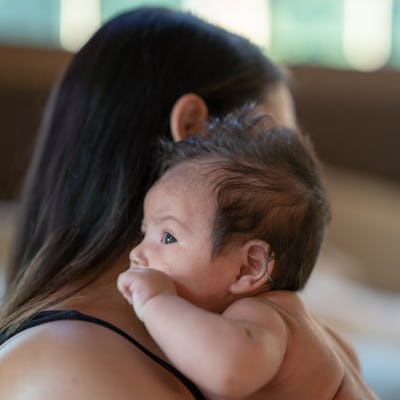A new mom holds her newborn baby cheek to cheek.