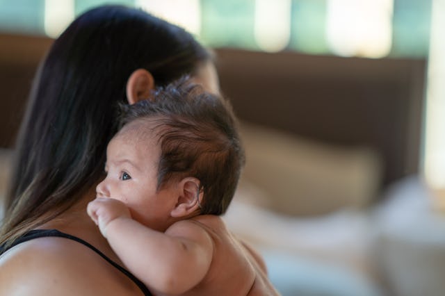 A new mom holds her newborn baby cheek to cheek.