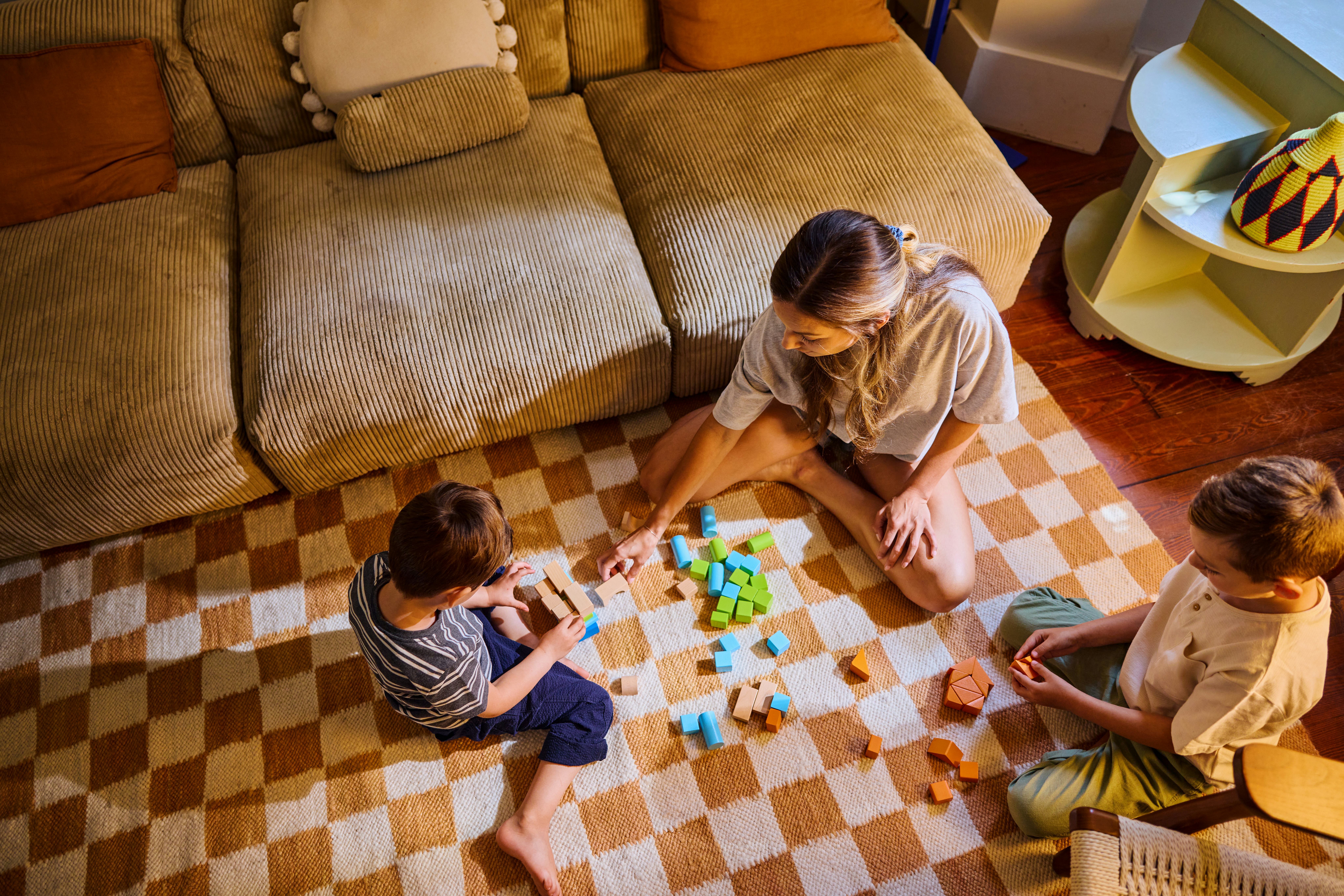 Mother and her two children enjoying quality time together, playing with colorful building blocks in their cozy living room