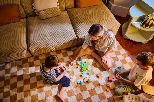 Mother and her two children enjoying quality time together, playing with colorful building blocks in...