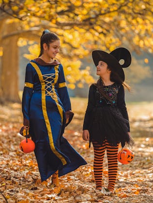Two young girls in Halloween costumes goes to trick or treating.