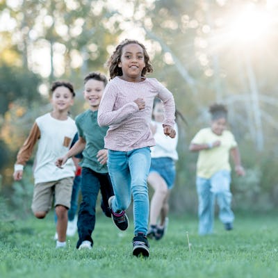 A joyful, diverse group of children runs together in a sunlit park, capturing energy, friendship, and active play. Perfect for family, school, or community wellness themes, highlighting inclusivity and outdoor activity.