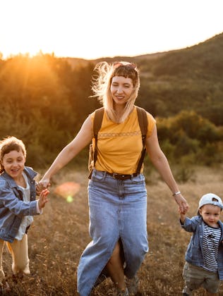 Photo of young mother spending time with her children by taking them for a walk in nature.