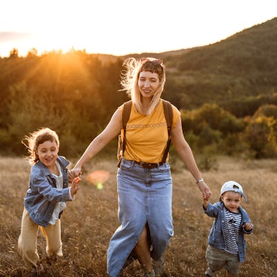 Photo of young mother spending time with her children by taking them for a walk in nature.
