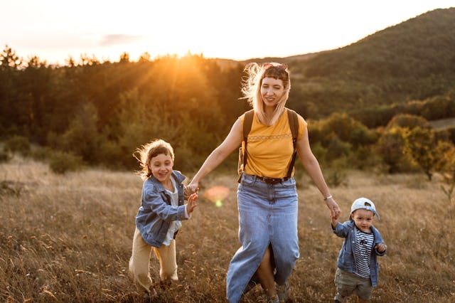 Photo of young mother spending time with her children by taking them for a walk in nature.