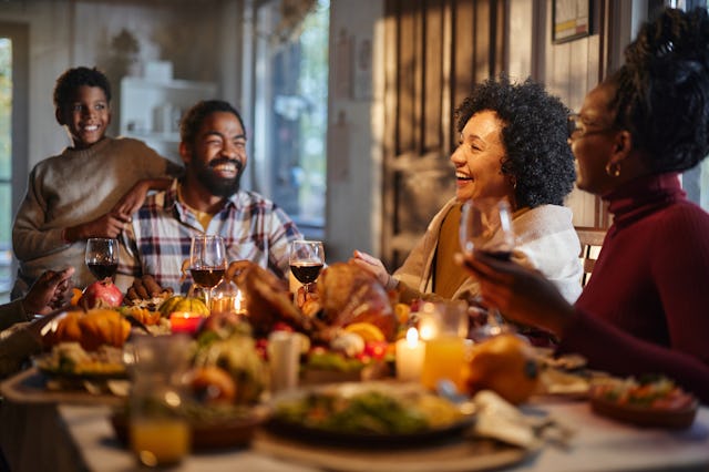 Happy African American extended family talking during Thanksgiving meal at dining table. Focus is on...
