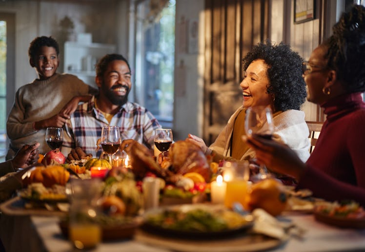 Happy African American extended family talking during Thanksgiving meal at dining table. Focus is on...
