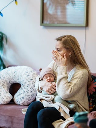 A woman holds her infant baby and wipes a tear from her cheek while talking with a other parents at ...