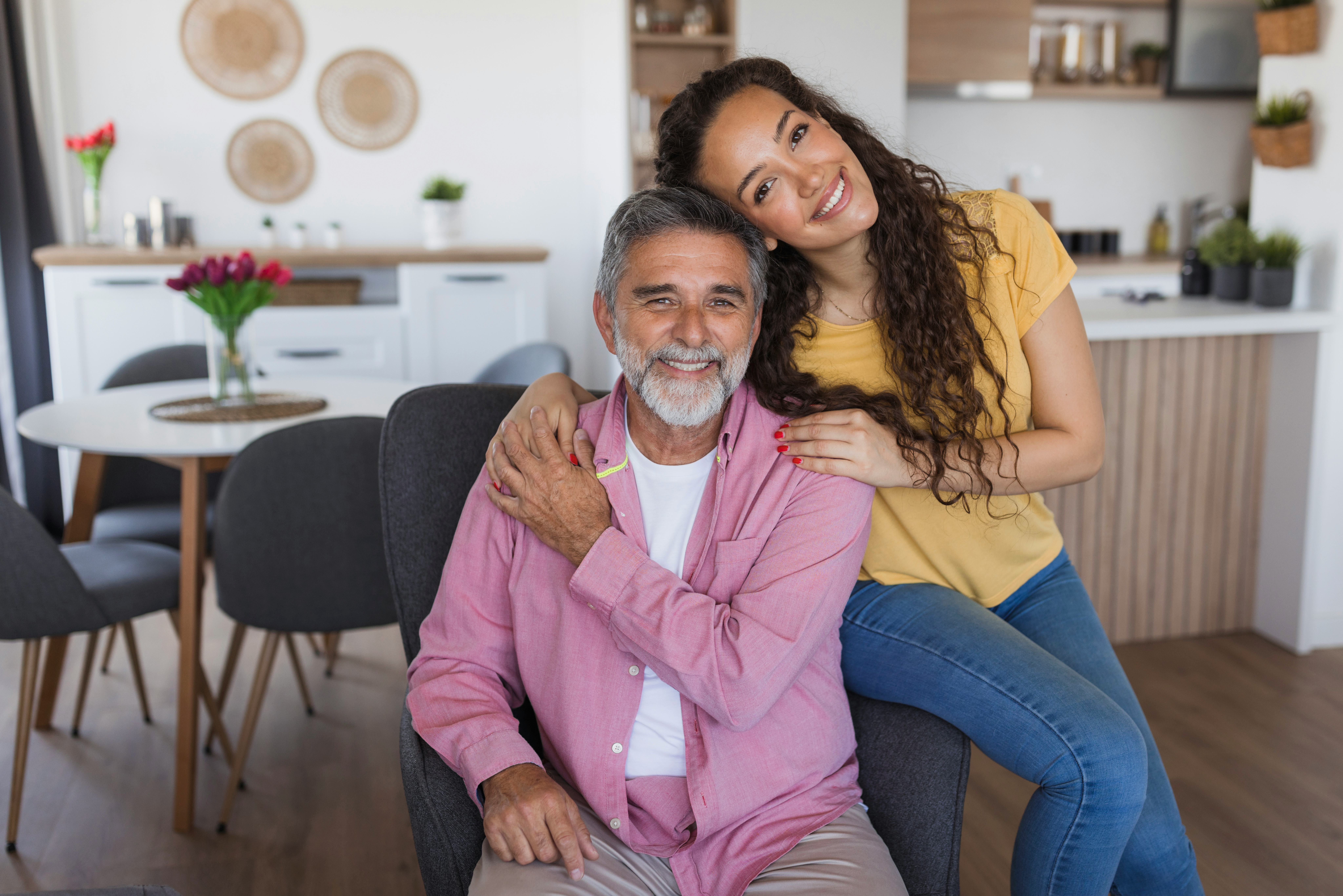 Happy father and daughter are smiling and embracing each other in their modern living room