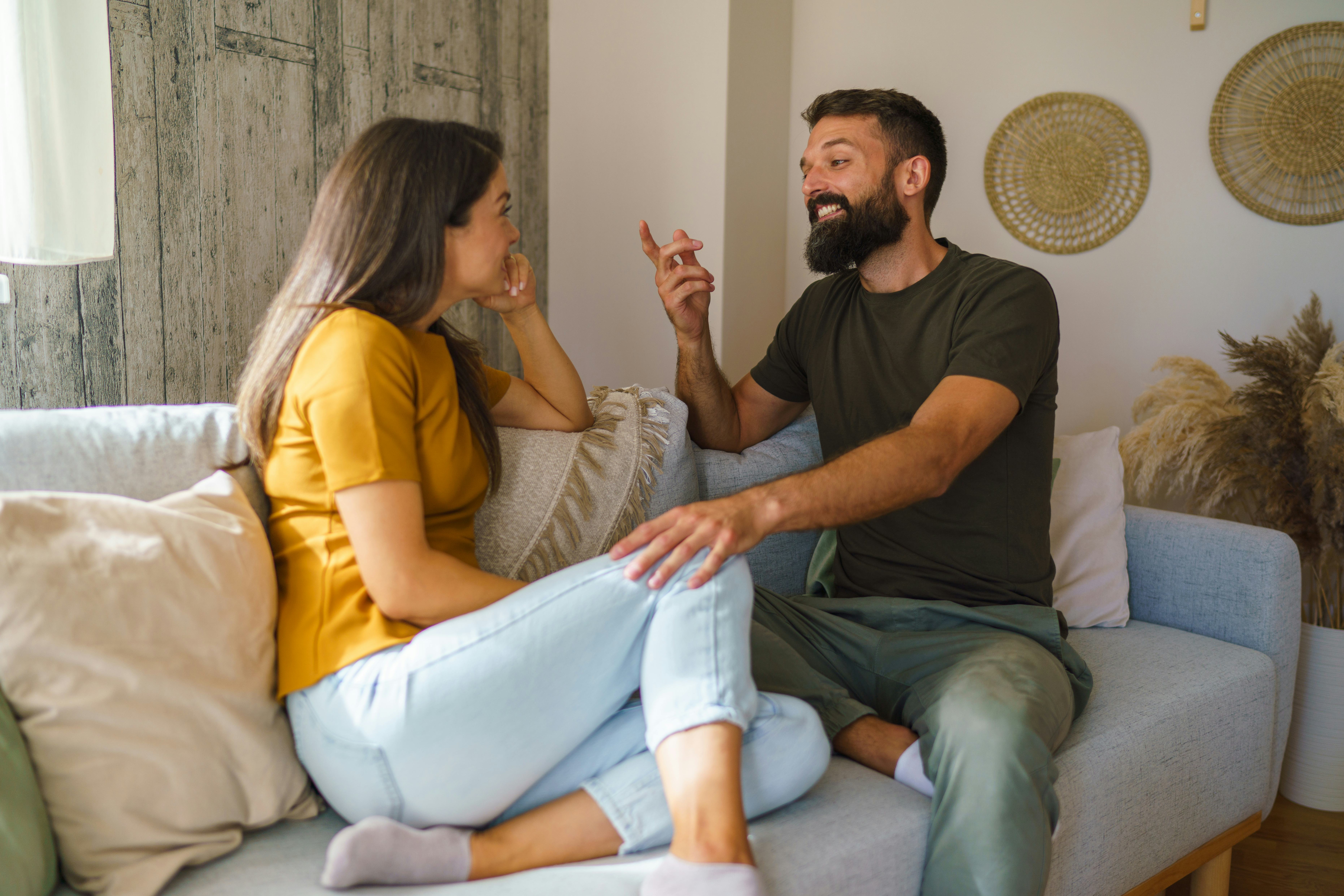 Young man and woman communicating, discussing relationships and laughing at home.