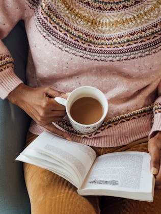 A high angle view of a mature woman sitting in a holiday rental. She is reading a book and has a hot...