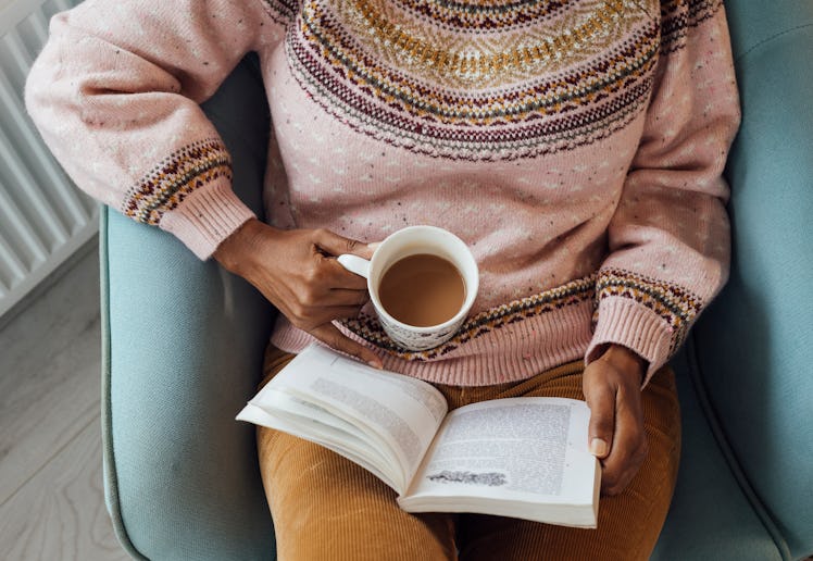 A high angle view of a mature woman sitting in a holiday rental. She is reading a book and has a hot...