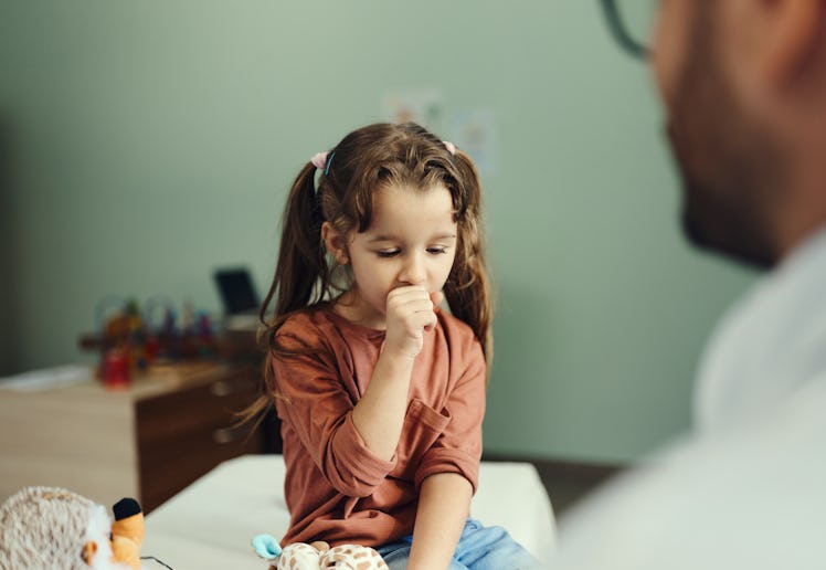 Little girl coughing in the doctor's office.