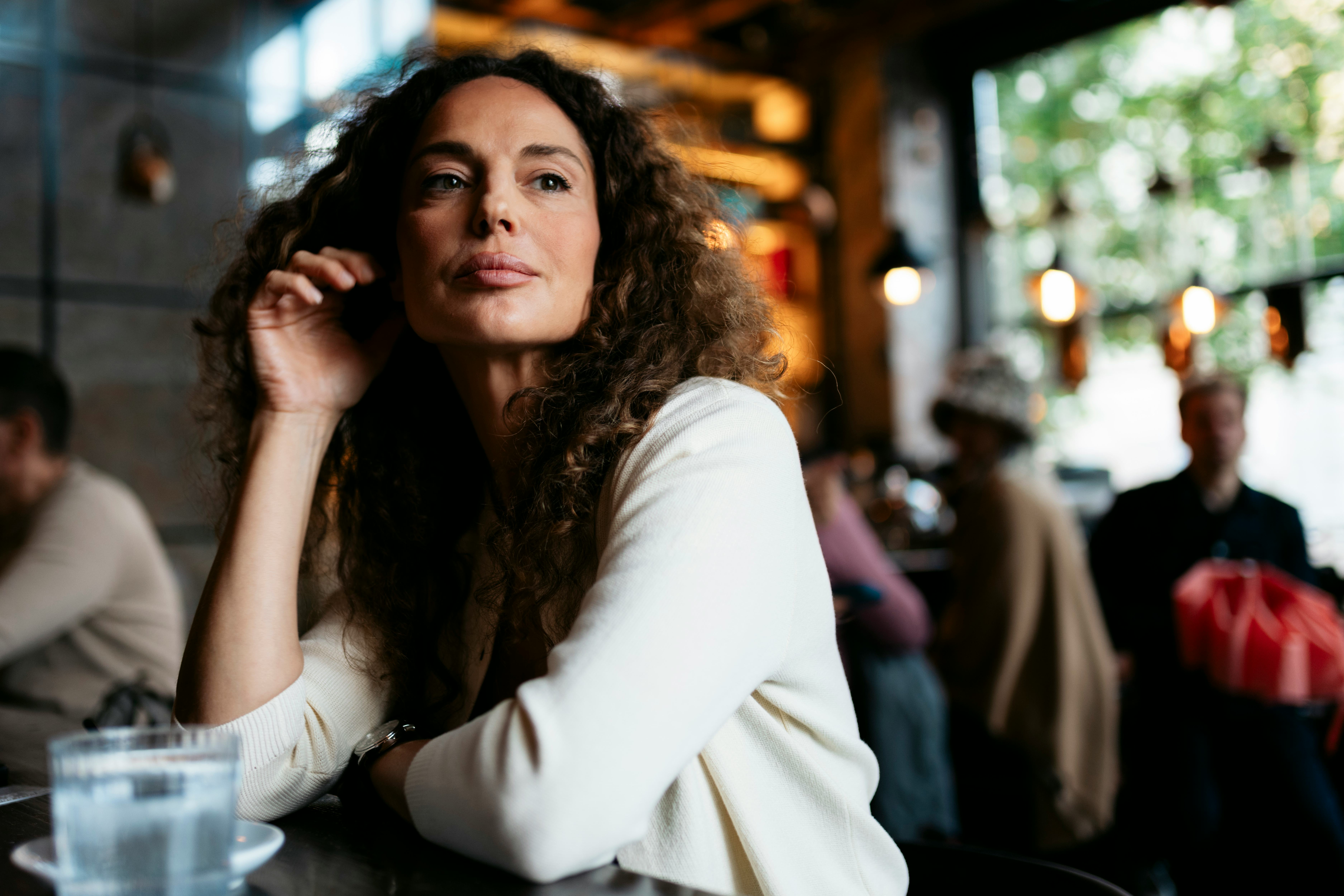 Mature woman sitting at a table with a thoughtful expression in a cafe