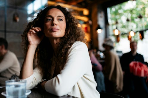 Mature woman sitting at a table with a thoughtful expression in a cafe