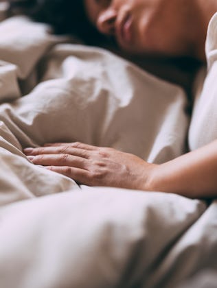 A serene image of a woman sleeping peacefully in bed, conveying comfort and rest. The soft lighting ...
