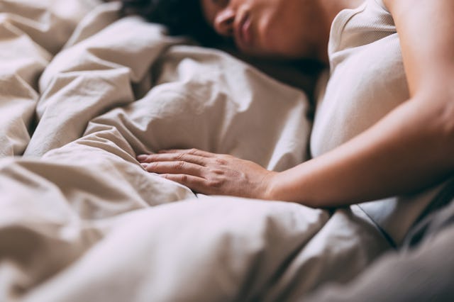 A serene image of a woman sleeping peacefully in bed, conveying comfort and rest. The soft lighting ...