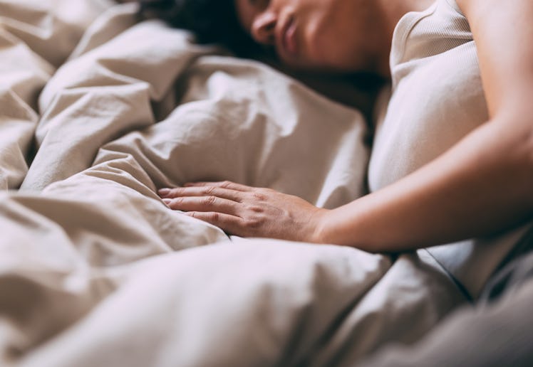 A serene image of a woman sleeping peacefully in bed, conveying comfort and rest. The soft lighting ...
