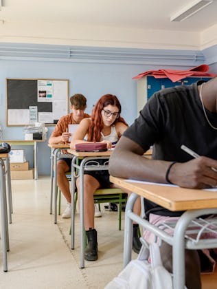 Medium group of high school students writing a test in the classroom.