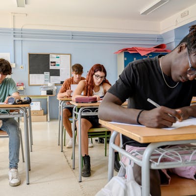 Medium group of high school students writing a test in the classroom.