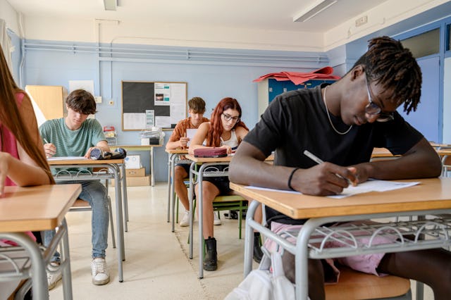 Medium group of high school students writing a test in the classroom.