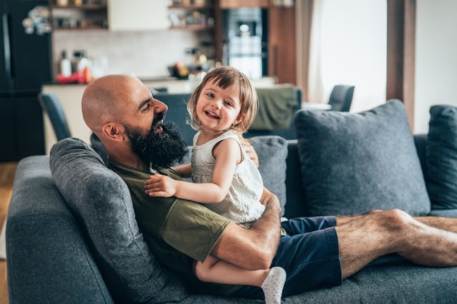 Young father and his toddler play on the couch.