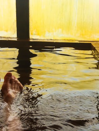 Female enjoying hot spring water against steamed window, personal perspective, just feet in water, H...