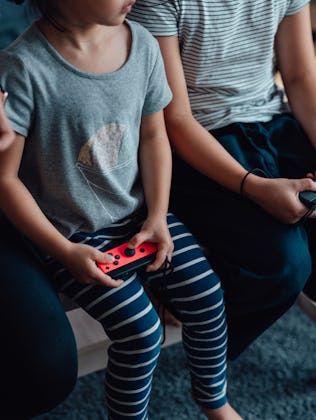 Cropped shot of mother and daughters holding game controllers, playing video games together. Enjoyin...
