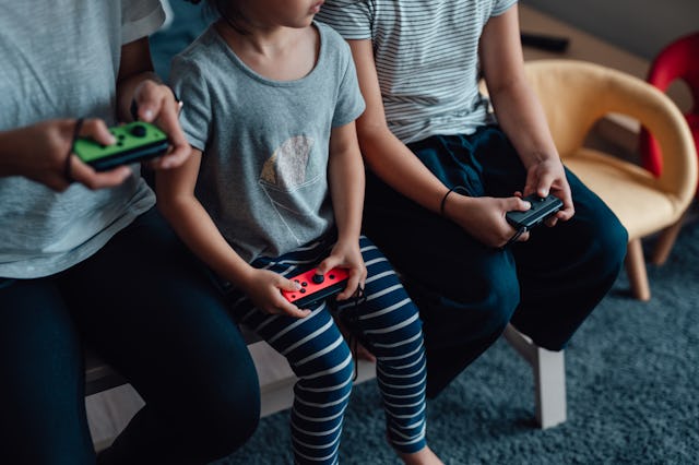 Cropped shot of mother and daughters holding game controllers, playing video games together. Enjoyin...
